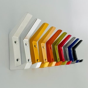 Pode incluir: Uma fila de 12 ganchos de metal em várias cores, incluindo prata, ouro, laranja, amarelo, verde, vermelho, azul e preto. Os ganchos estão dispostos em um padrão escalonado, com o gancho prateado na frente e o gancho preto atrás.