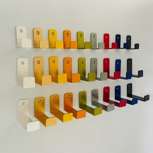 May include: A wall mounted set of 24 hooks in various colors, including silver, gold, red, and blue. The hooks are arranged in rows and are all the same size and shape.