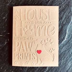 Puede incluir: Una tarjeta marr&oacute;n con el texto "Una casa no es un hogar sin huellas de patas" y una silueta de un perro con un coraz&oacute;n rojo en el pecho.
