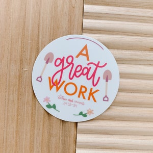 May include: A round sticker with the words "A great WORK" in pink and orange script. Two pink shovels flank the text. The sticker also includes the text "Doctrine and covenants 64:33-34" and floral accents.