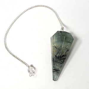 May include: A green and black crystal pendulum with a silver chain. The crystal is faceted and has a pointed tip.