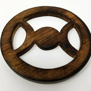 May include: A dark brown wooden circle with a triple moon symbol carved out in the center.