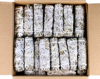 May include: A cardboard box filled with white sage smudge sticks. The sticks are tied together with white string and are arranged in rows.