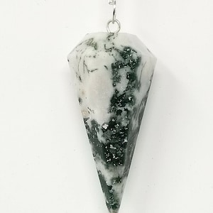 May include: A faceted pendulum made of white and green speckled stone, suspended from a silver-colored chain. The pendulum has a conical shape with a pointed tip and is designed for divination or spiritual practices.