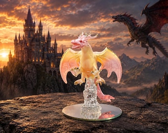 May include: A translucent dragon figurine featuring a pale pink and yellow gradient body with gold-toned accents on the horns, claws, and wing edges. The creature is perched atop a clear, textured crystalline base resting on a circular mirror.