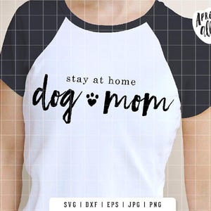 May include: White and black raglan style t-shirt with the text "stay at home dog mom" in black script. The shirt features a paw print graphic and the brand name "Apricot Ally".