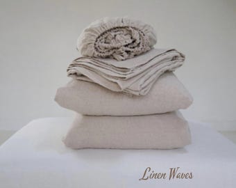 Puede incluir: Una pila de ropa de cama de lino beige, que incluye una sábana bajera, una sábana plana y fundas de almohada. La ropa de cama está doblada cuidadosamente y dispuesta sobre una superficie blanca. El texto "Linen Waves" es visible en la parte inferior de la imagen.
