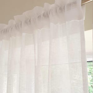 Può includere: Pannelli di tende bianche trasparenti con un dettaglio a balze sulla parte superiore, appesi a un'asta argentata. Le tende sono realizzate in un tessuto leggero, che permette alla luce naturale di filtrare. Il design è semplice ed elegante, adatto a vari stili di interni.