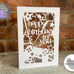Puede incluir: Tarjeta blanca con un diseño recortado de un mando de videojuego, estrellas y las palabras "feliz cumpleaños para ti".