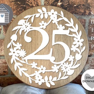 Puede incluir: Un letrero redondo de madera con el número 25 recortado en blanco, rodeado por una corona floral. El letrero incluye el texto "SVG, DXF, EPS, PNG, PDF" y "DESCARGA DIGITAL".