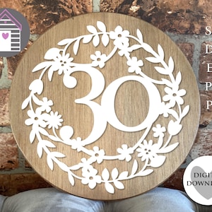 Pode incluir: Uma placa redonda de madeira com acabamento castanho claro. O número "30" é recortado em branco, rodeado por uma coroa de flores. A placa também inclui o texto "SVG, DXF, EPS, PNG, PDF" e "DOWNLOAD DIGITAL".