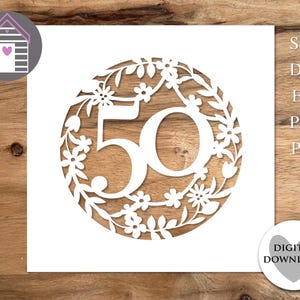 May include: A white paper cut-out design showing the number "50" surrounded by a floral wreath. The design is set against a wooden background. Includes digital download options: SVG, DXF, EPS, PNG, and PDF.