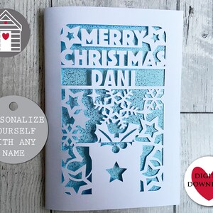 May include: A white card with a blue background and a cut-out design of snowflakes, stars, and the words "Merry Christmas Dani".
