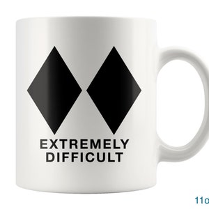 May include: White ceramic mug with two black diamond symbols and the text "EXTREMELY DIFFICULT" printed on the front. The mug is 11 ounces.
