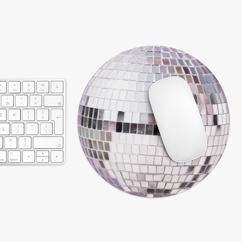 K&ouml;nnte beinhalten: Eine wei&szlig;e Computermaus liegt auf einem runden, silbernen Discokugel-Mauspad. Das Mauspad hat eine spiegelnde Oberfl&auml;che mit kleinen, quadratischen Fliesen.