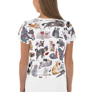 May include: White crop top with a repeating pattern of cats drinking wine. The cats are in various poses and have different colored fur.
