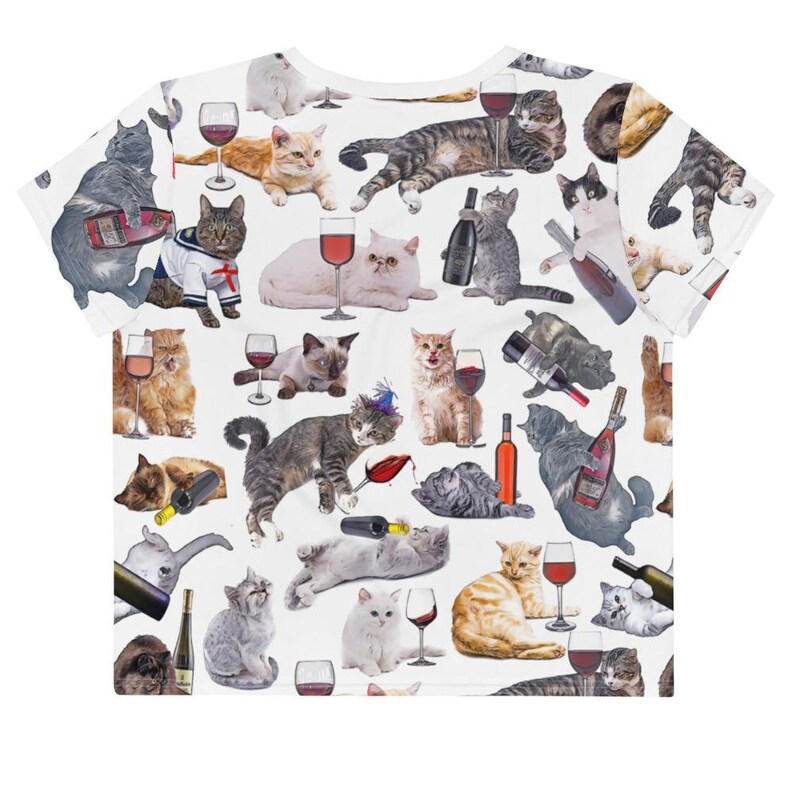 May include: White crop top with a repeating pattern of cats drinking wine. The cats are in various poses and have different colored fur. The wine glasses are filled with red wine.