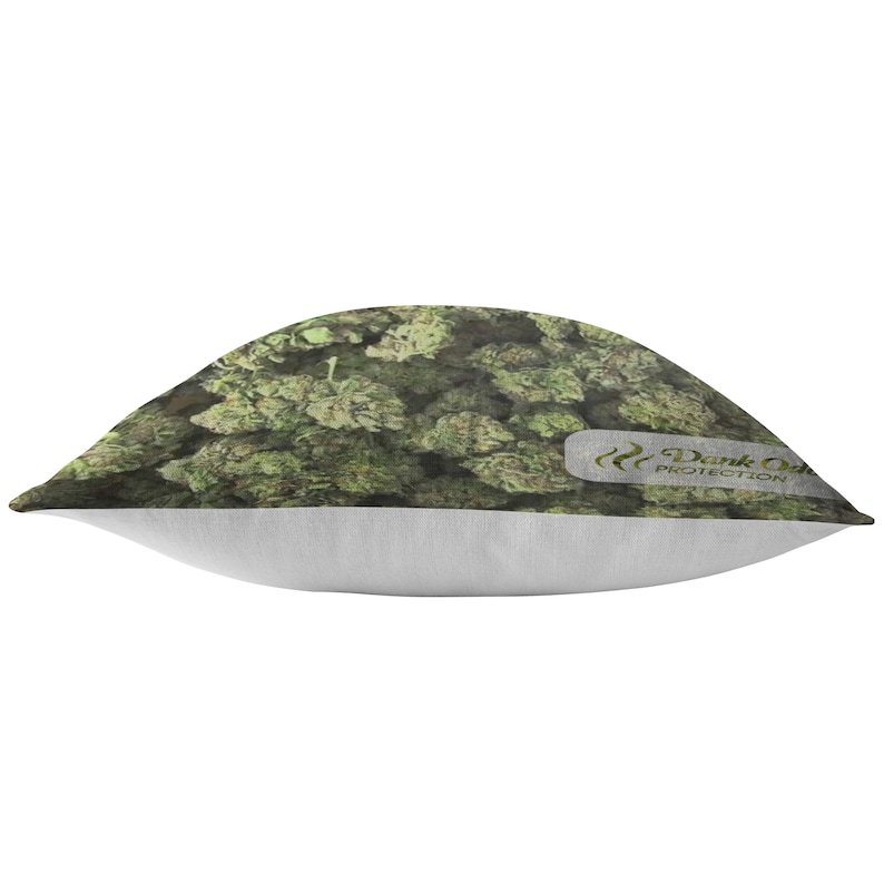 Peut inclure: Un coussin de d&eacute;coration vert et blanc avec un motif de feuilles de marijuana. Le coussin a une bordure blanche et le texte "Dank Odor Protection" en vert.