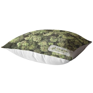 Peut inclure: Un oreiller blanc avec un imprim&eacute; vert et brun de bourgeons de marijuana. L'oreiller a une &eacute;tiquette blanche avec le texte "Dank Odor Protection" dessus.