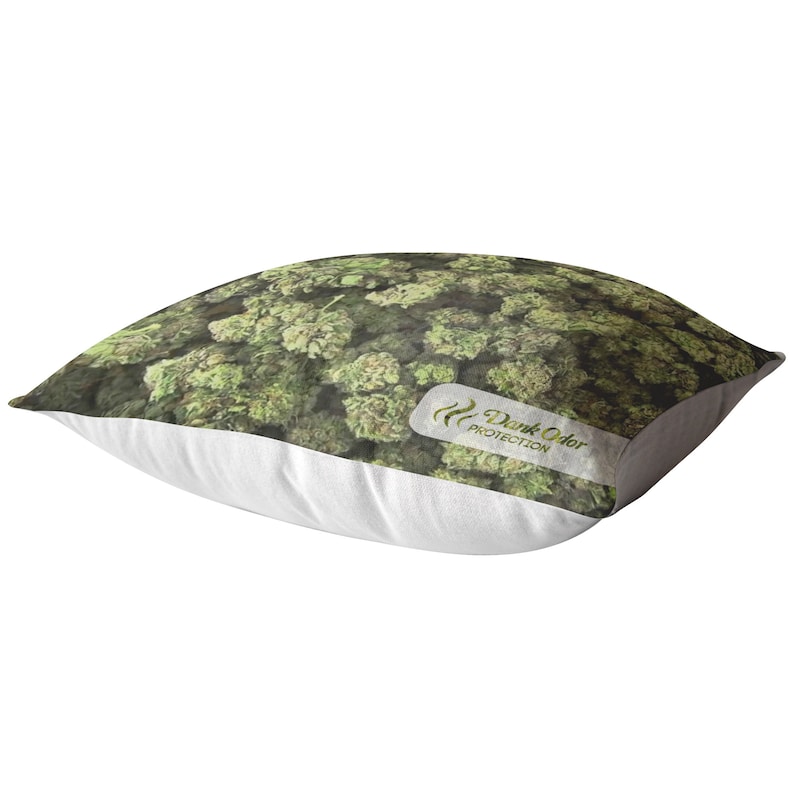 Peut inclure: Un oreiller blanc avec un imprim&eacute; vert et brun de bourgeons de marijuana. L'oreiller a une &eacute;tiquette blanche avec le texte "Dank Odor Protection" dessus.