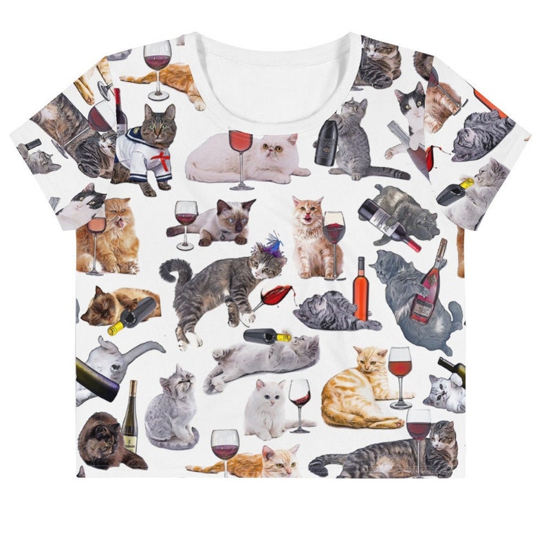 May include: White crop top with a repeating pattern of cats drinking wine. The cats are in various poses and have different colored fur. Some cats are wearing party hats.