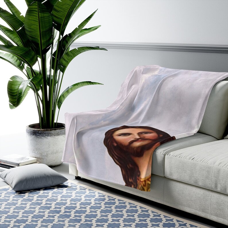 Puede incluir: Una manta de forro polar blanca con una imagen impresa de Jesucristo. La imagen es de estilo vintage y presenta un primer plano de la cara y el cabello largo de Jes&uacute;s.