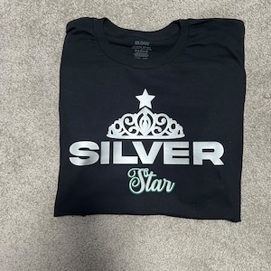 May include: Black t-shirt with a silver crown and the text "SILVER Star" in a green cursive font.