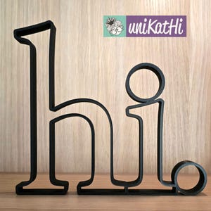 May include: Black metal cutout of the word "hi" with a rounded "i".
