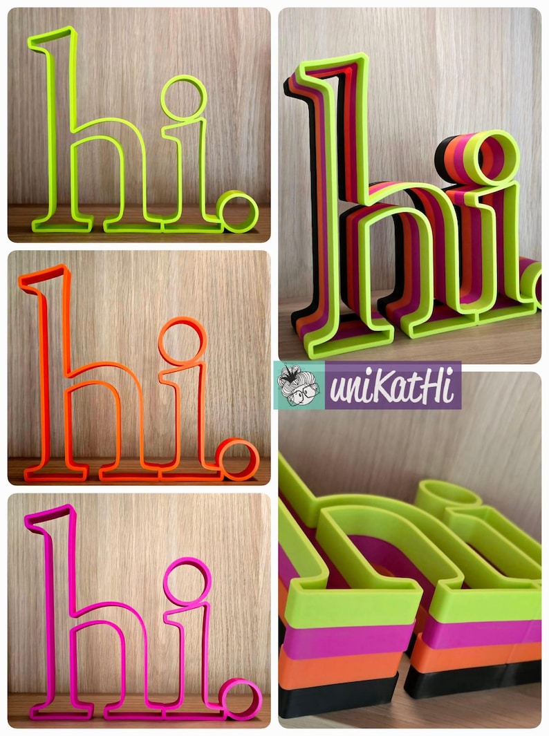 May include: Four different colored 3D printed "hi" signs. The signs are layered and made of green, orange, pink, and black plastic.
