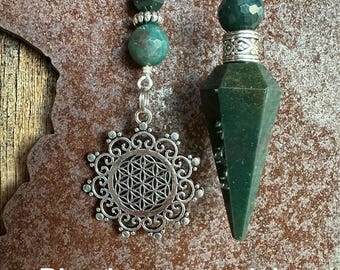 May include: Two green bloodstone pendulums, one with a silver flower of life charm and the other with a pointed tip.  Bloodstone pendulum.
