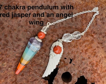 May include: A silver chain with a clear crystal bead and a silver angel wing charm with a red jasper stone. The chain is attached to a seven chakra pendulum with a pointed tip and a red jasper stone at the top.