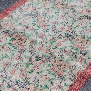 Puede incluir: Una alfombra vintage con estampado floral y borde rojo. La alfombra tiene un fondo crema con dise&ntilde;os florales verdes, rosas y negros.