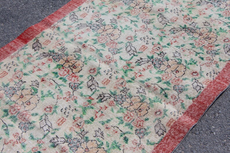 Puede incluir: Una alfombra vintage con estampado floral y borde rojo. La alfombra tiene un fondo crema con dise&ntilde;os florales verdes, rosas y negros.