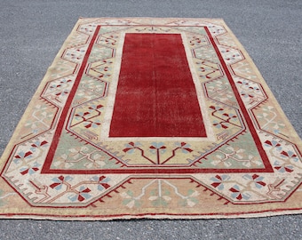 May include: A vintage rug with a red center and a beige border with a geometric pattern. The rug has a worn look and is made of wool.