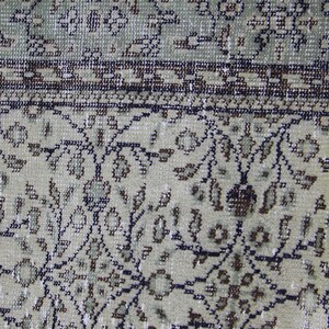 Puede incluir: Primer plano de una alfombra beige con un patr&oacute;n floral. La alfombra tiene un borde marr&oacute;n oscuro con un dise&ntilde;o geom&eacute;trico.