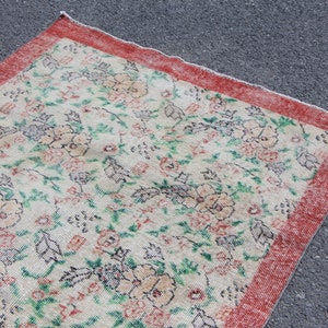 Puede incluir: Una alfombra vintage con un patr&oacute;n floral en tonos de rosa, verde y blanco. La alfombra tiene un borde rojo.