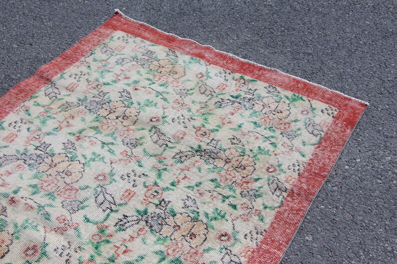 Puede incluir: Una alfombra vintage con un patr&oacute;n floral en tonos de rosa, verde y blanco. La alfombra tiene un borde rojo.