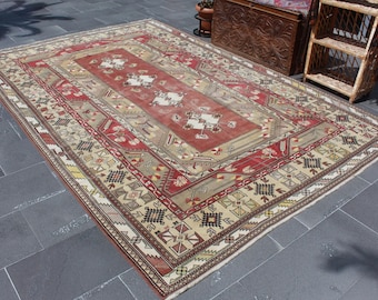 May include: A vintage Turkish rug with a beige background and intricate red, white, and black geometric patterns. The rug has a worn and faded look, adding to its charm.