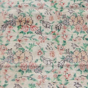 Puede incluir: Una alfombra vintage con un patr&oacute;n floral en tonos rojos, verdes y blancos. La alfombra tiene un fondo crema y un borde rojo.
