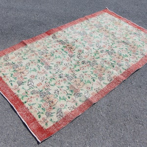 Puede incluir: Una alfombra floral vintage con fondo crema y borde rojo. La alfombra presenta un patr&oacute;n repetitivo de flores y hojas en tonos verdes, rosas y marrones.