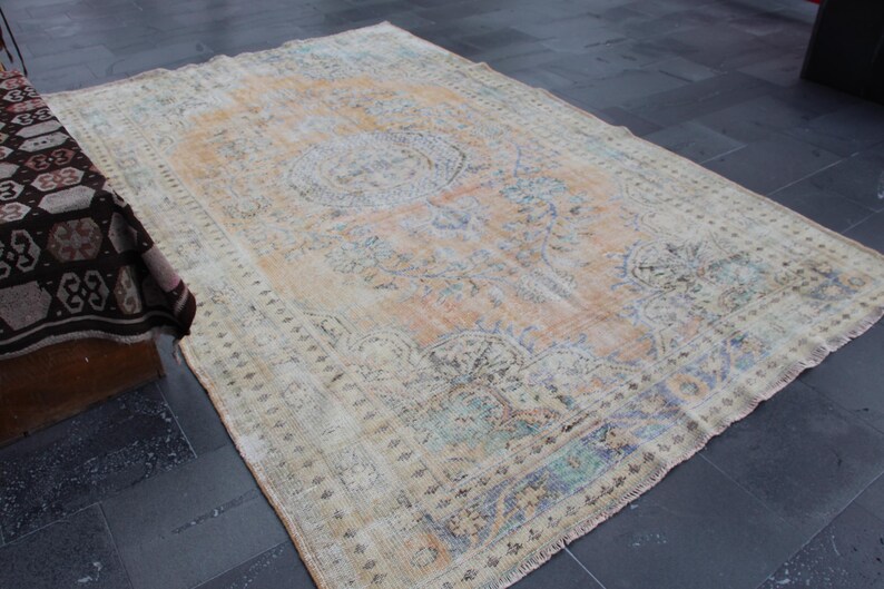 May include: A vintage rug with a faded floral pattern in shades of beige, blue, and green. The rug has a distressed look and is made of wool.