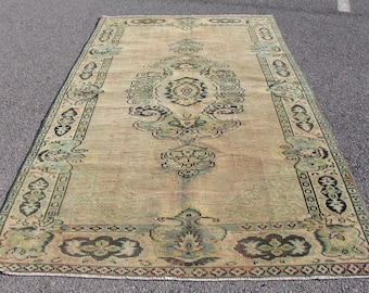 May include: A vintage rug with a beige background and a green and black floral pattern. The rug has a distressed look and is perfect for adding a touch of bohemian style to any room.