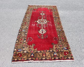 May include: A vintage red rug with a floral pattern and a dark brown border. The rug has a distressed look and is made of wool.
