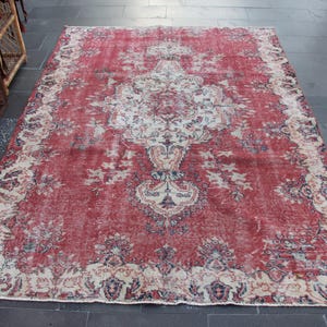 May include: A vintage red and cream area rug with a floral pattern. The rug has a distressed look and is made of wool.