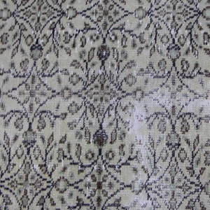 Puede incluir: Primer plano de una alfombra beige con un patr&oacute;n floral en tonos marrones y negros. La alfombra tiene un aspecto desgastado y vintage.