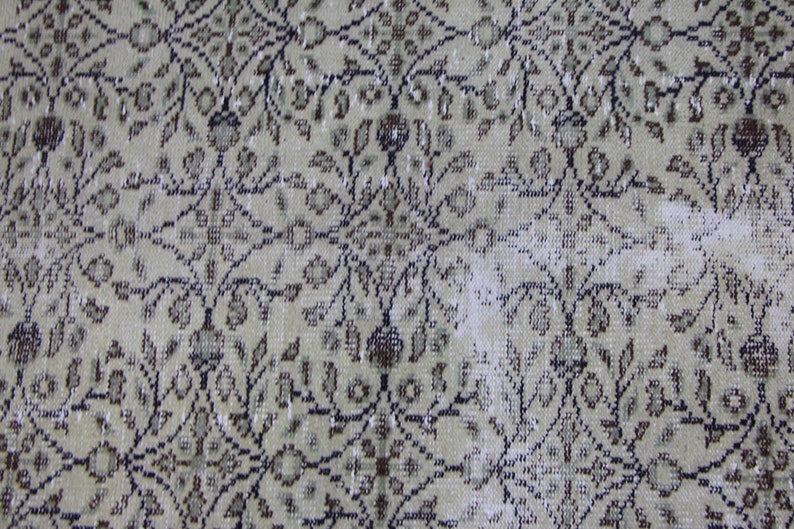 Puede incluir: Primer plano de una alfombra beige con un patr&oacute;n floral en tonos marrones y negros. La alfombra tiene un aspecto desgastado y vintage.