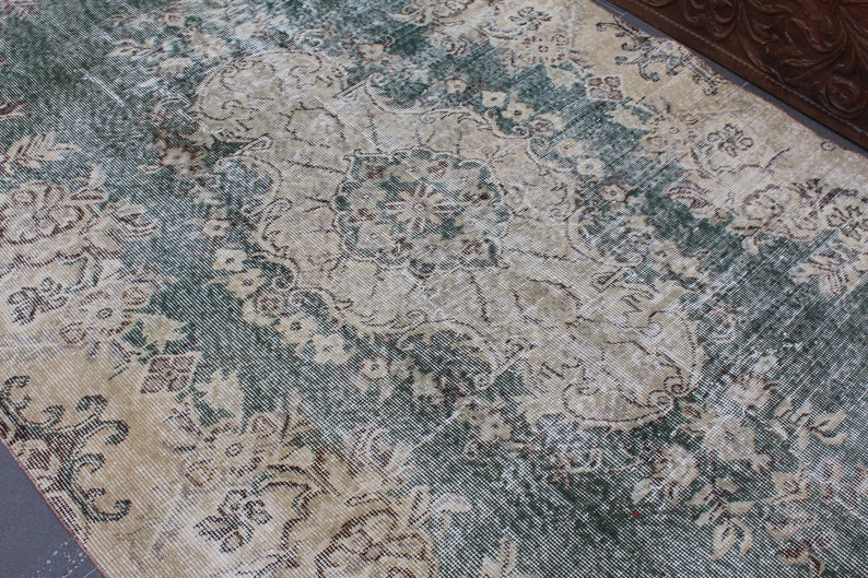 May include: A vintage rug with a faded floral pattern in shades of beige, brown, and green. The rug has a distressed look and is made of a soft, woven material.