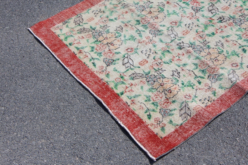 Puede incluir: Una alfombra vintage con estampado floral y borde rojo. La alfombra tiene un fondo crema con dise&ntilde;os florales verdes y rosas.