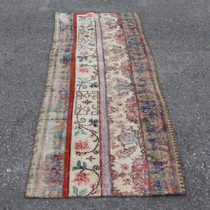 May include: A vintage rug with a cream background and colorful floral and geometric patterns. The rug has a red border and a faded, distressed look.