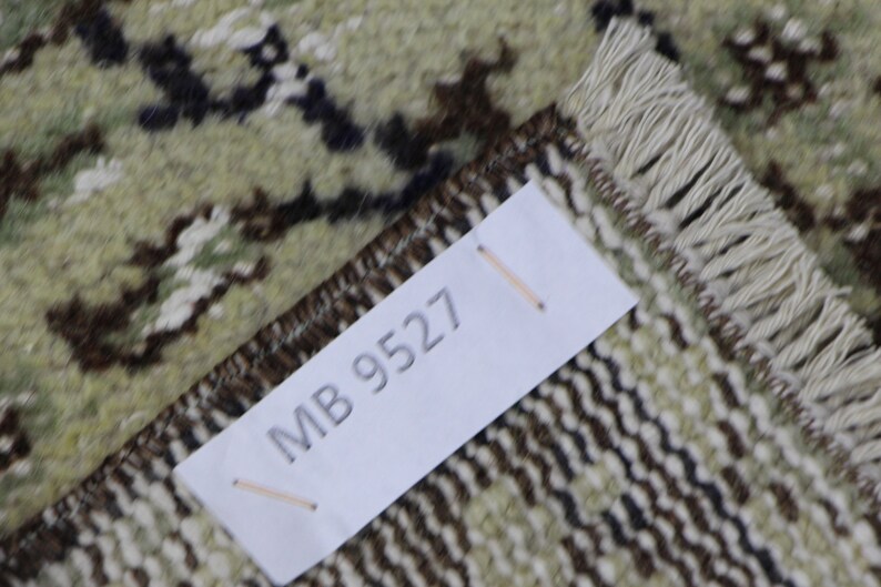 Puede incluir: Primer plano de una alfombra con un patr&oacute;n marr&oacute;n y blanco. Una etiqueta blanca con el texto "MB 9527" est&aacute; unida a la alfombra.